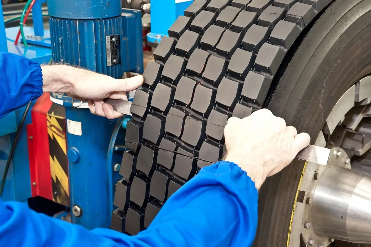 Technician measuring new tread on a retreaded truck tyre